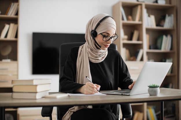 A certified Quran tutor taking notes during an online class